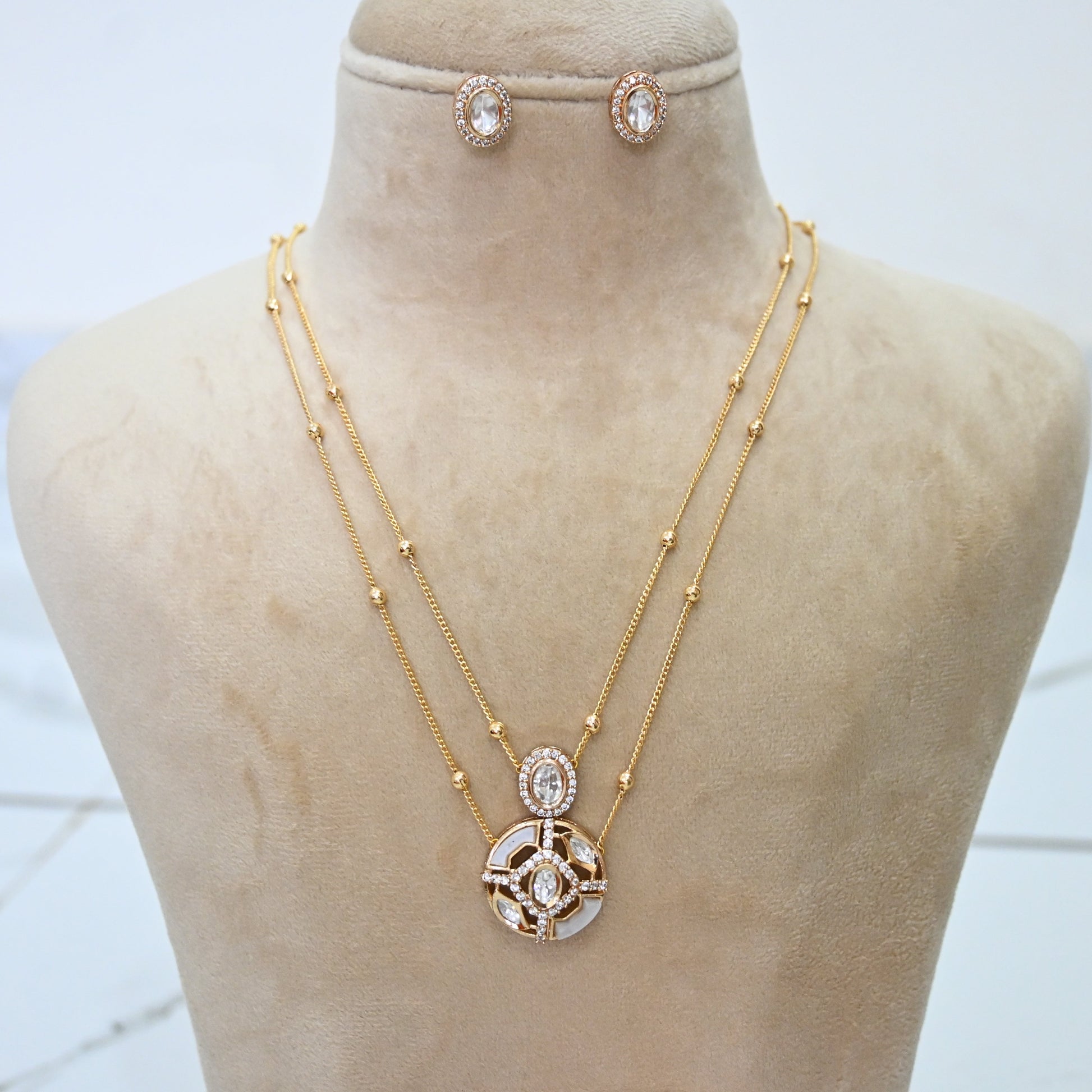 Gold tone double layer satellite chain necklace with crystal medallion pendant and matching oval stud earrings"